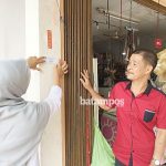 Julita memasangkan setiker SITU di kedai Mimi Dabo Singkep f Wijaya